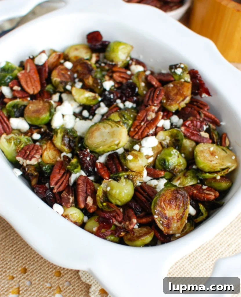 Crispy Brussels Sprouts with Tangy Cranberries 2 A white bowl filled with perfectly roasted Brussels Sprouts with Cranberries, crumbled blue cheese, and chopped pecans, ready to be served.