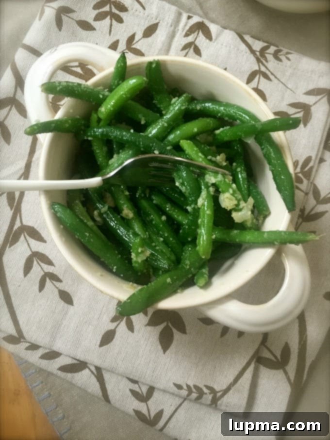 Effortless Garlic Parmesan Green Beans 4 A bowl of hot garlic parmesan green beans garnished with extra cheese, ready to be served.