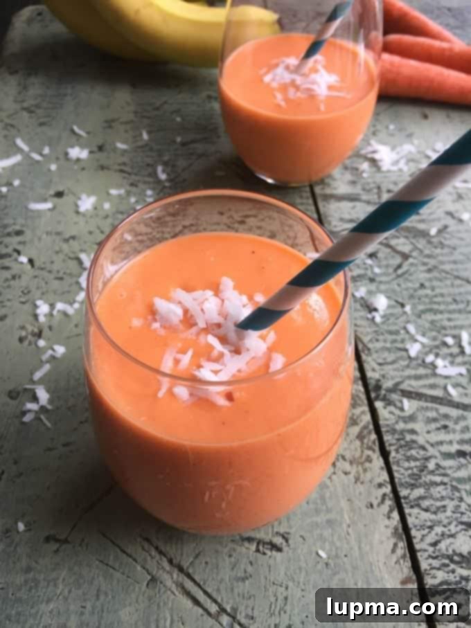 11 Irresistibly Refreshing Smoothies 3 A creamy, orange-hued Coconut Carrot Smoothie in a glass, garnished with a carrot top.
