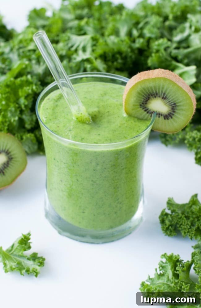 11 Irresistibly Refreshing Smoothies 4 A vibrant green Tropical Mango Kale Smoothie in a glass with a straw, beside fresh mango and kale.