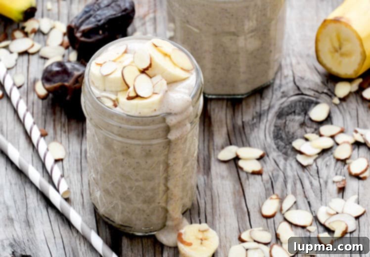 11 Irresistibly Refreshing Smoothies 5 A creamy Roasted Banana and Almond Smoothie in a clear glass, topped with sliced almonds.