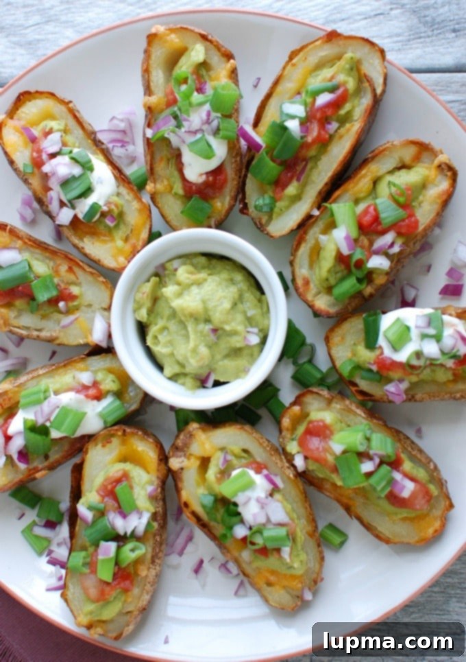 Zesty Guacamole Potato Skins 2 Close-up of Guacamole Stuffed Potato Skins on a white platter, garnished with fresh ingredients.