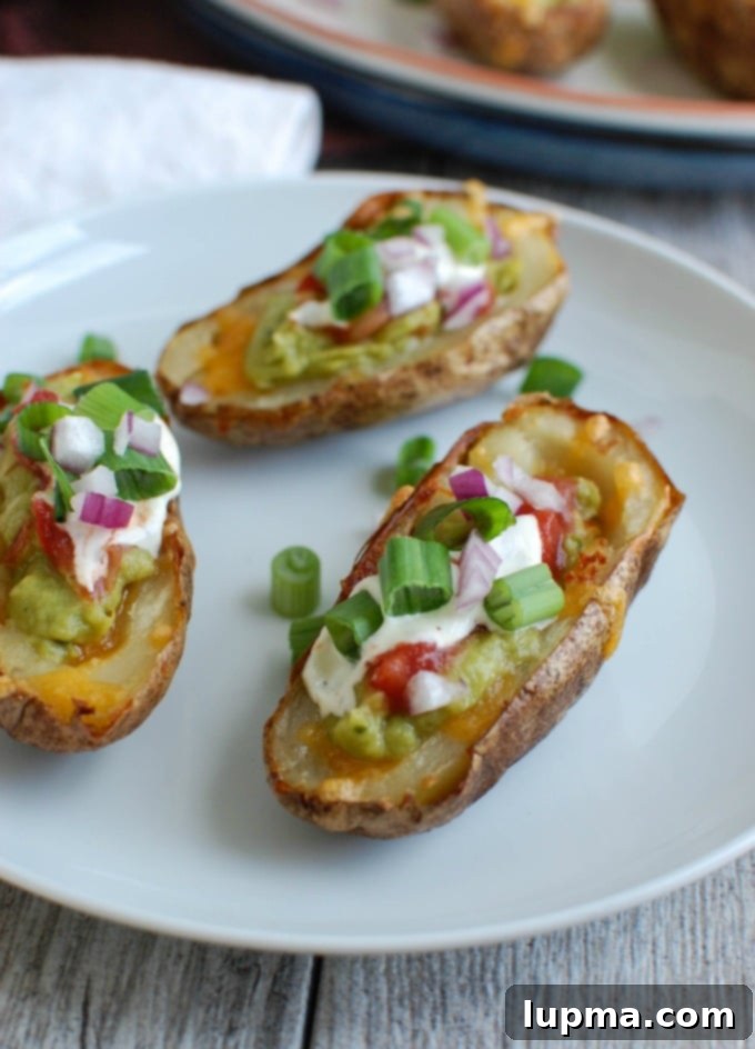 Zesty Guacamole Potato Skins 5 Three Guacamole Stuffed Potato Skins on a white plate with fresh cilantro garnish.
