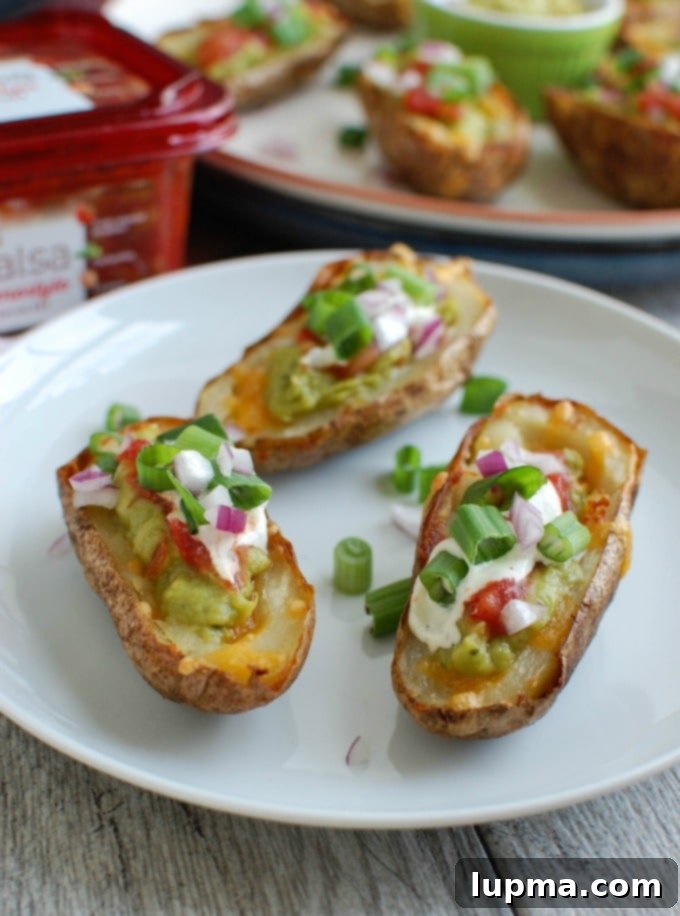 Zesty Guacamole Potato Skins 7 Three Guacamole Stuffed Potato Skins artfully arranged on a white plate, ready for serving.