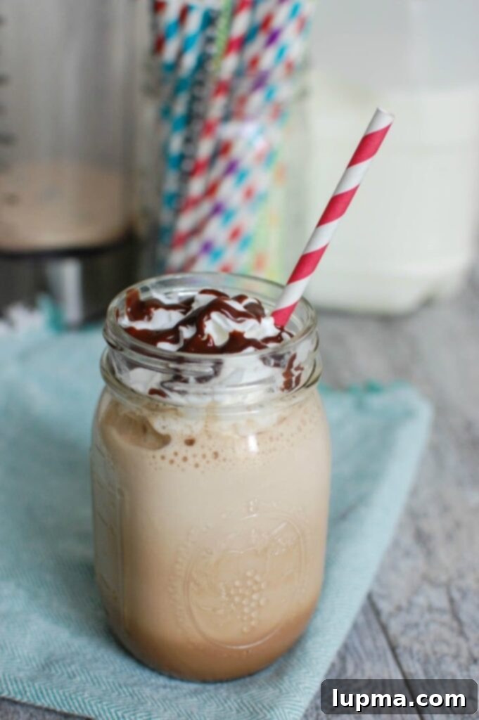 Delicious homemade mocha frappuccino in a glass with whipped cream and chocolate drizzle.