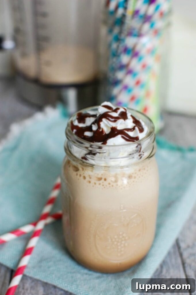 Close-up of a homemade mocha frappuccino with a generous swirl of whipped cream and chocolate sauce drizzle, ready to be enjoyed.