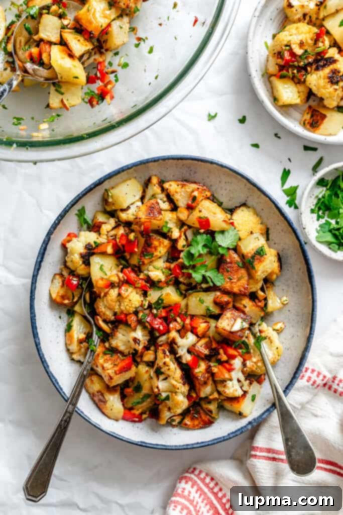 Creamy Cauliflower Potato Salad 2 Cauliflower Potato Salad in a rustic white bowl with a wooden spoon, showcasing roasted vegetables and a vibrant sauce