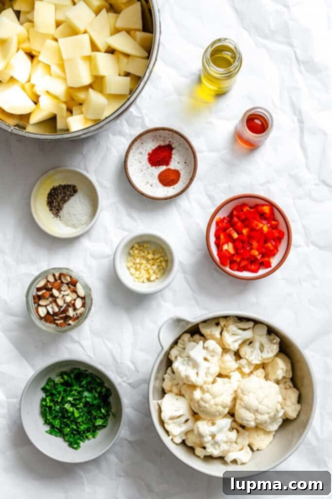 Creamy Cauliflower Potato Salad 3 Various fresh ingredients for Cauliflower Potato Salad, including cauliflower florets, diced potatoes, piquillo peppers, fresh parsley, and almonds