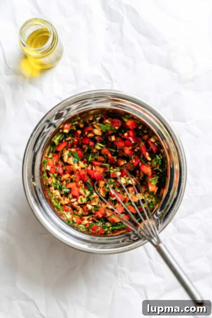 Creamy Cauliflower Potato Salad 7 Ingredients for the piquillo pepper sauce in a bowl, showing chopped peppers, parsley, almonds, and spices