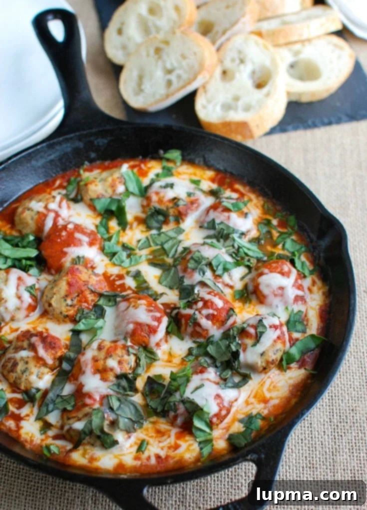 Garden Fresh Skillet Tomato Basil Meatballs 4 Hands serving a warm skillet of tomato basil meatballs with fresh baguette, showcasing the gooey cheese and rich sauce.