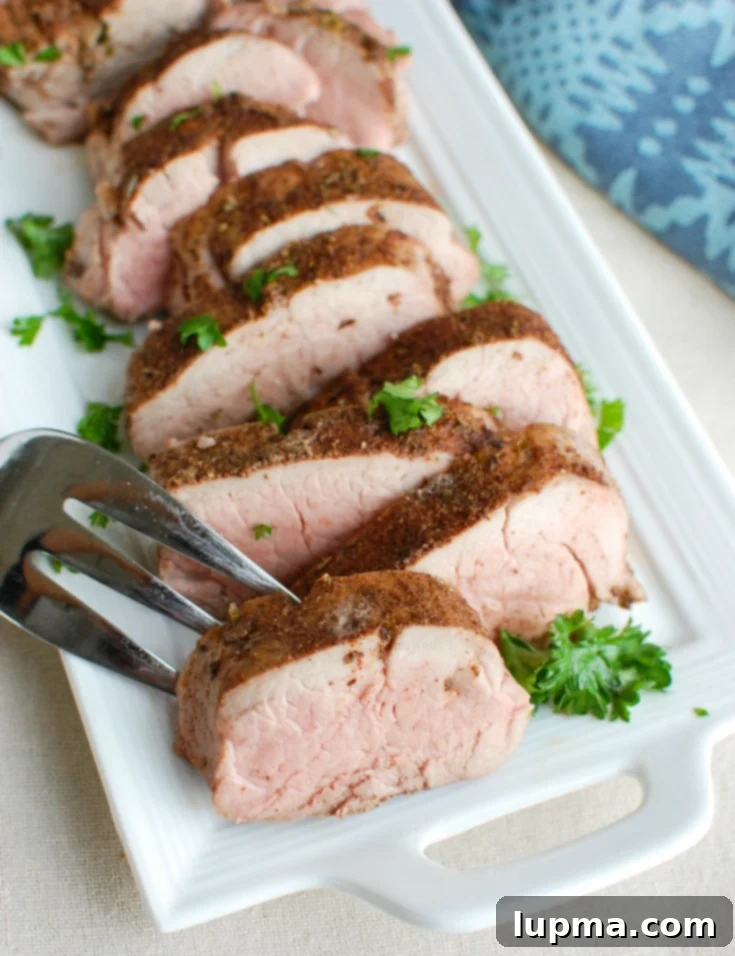 Sun-Drenched Mediterranean Pork Tenderloin 5 Sliced Mediterranean Baked Pork Tenderloin garnished with fresh parsley on a white platter, ready to serve.