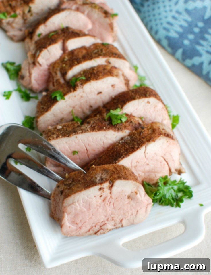 Sun-Drenched Mediterranean Pork Tenderloin 6 Close-up of a fork lifting a piece of perfectly cooked Mediterranean Baked Pork Tenderloin, showcasing its tender texture.