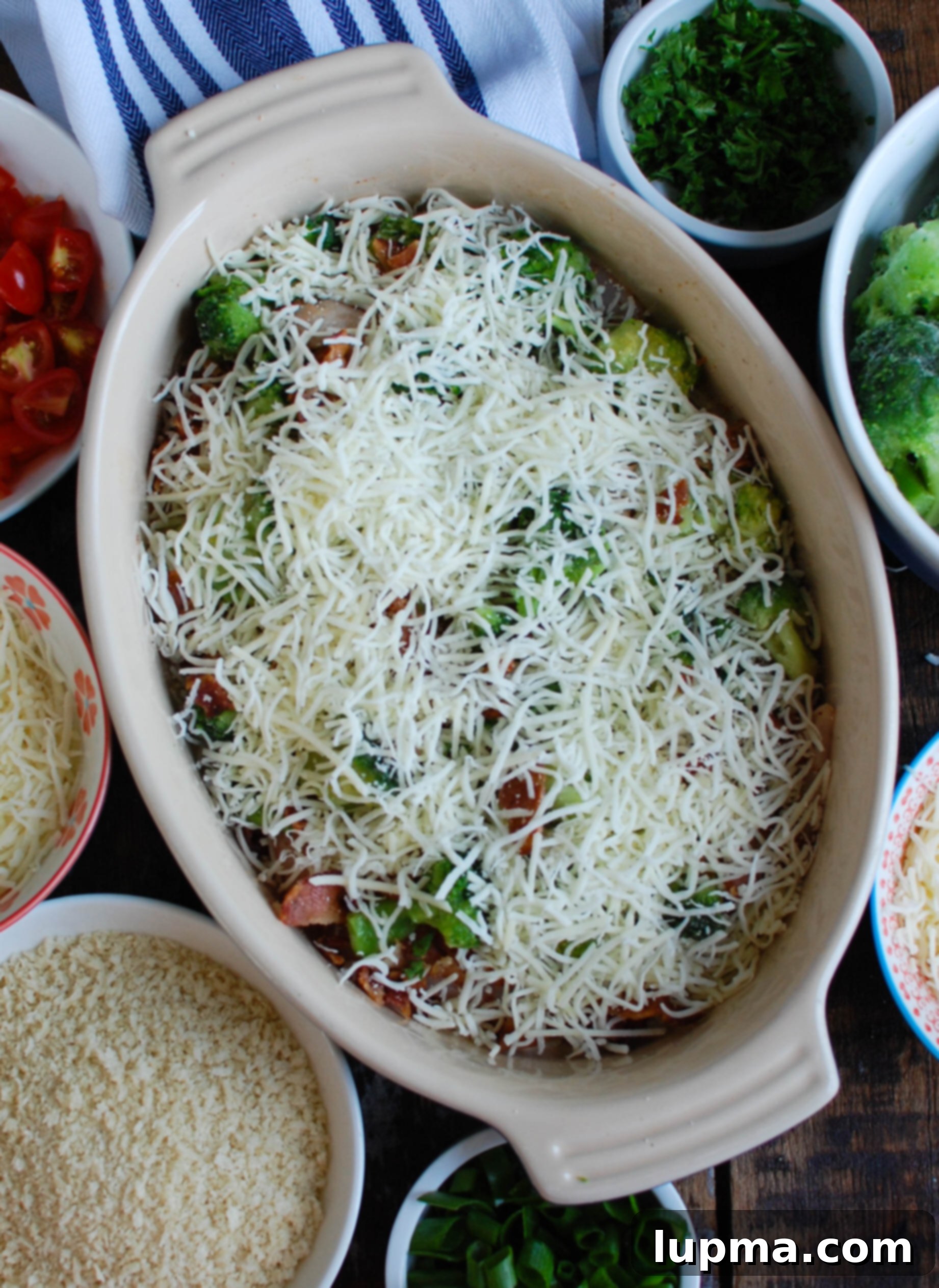 Cheesy Broccoli Chicken Bake 6 Baked Broccoli Cheese Chicken topped with Sargento shredded cheese and panko breadcrumbs, ready for the oven to create a golden, bubbly crust.