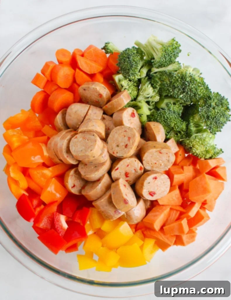 Golden Roasted Chicken Sausage and Garden Veggies 3 Close-up of fresh ingredients for Sheet Pan Chicken Sausage and Vegetables, including sliced chicken sausage, chopped sweet potatoes, broccoli florets, bell peppers, and carrots.