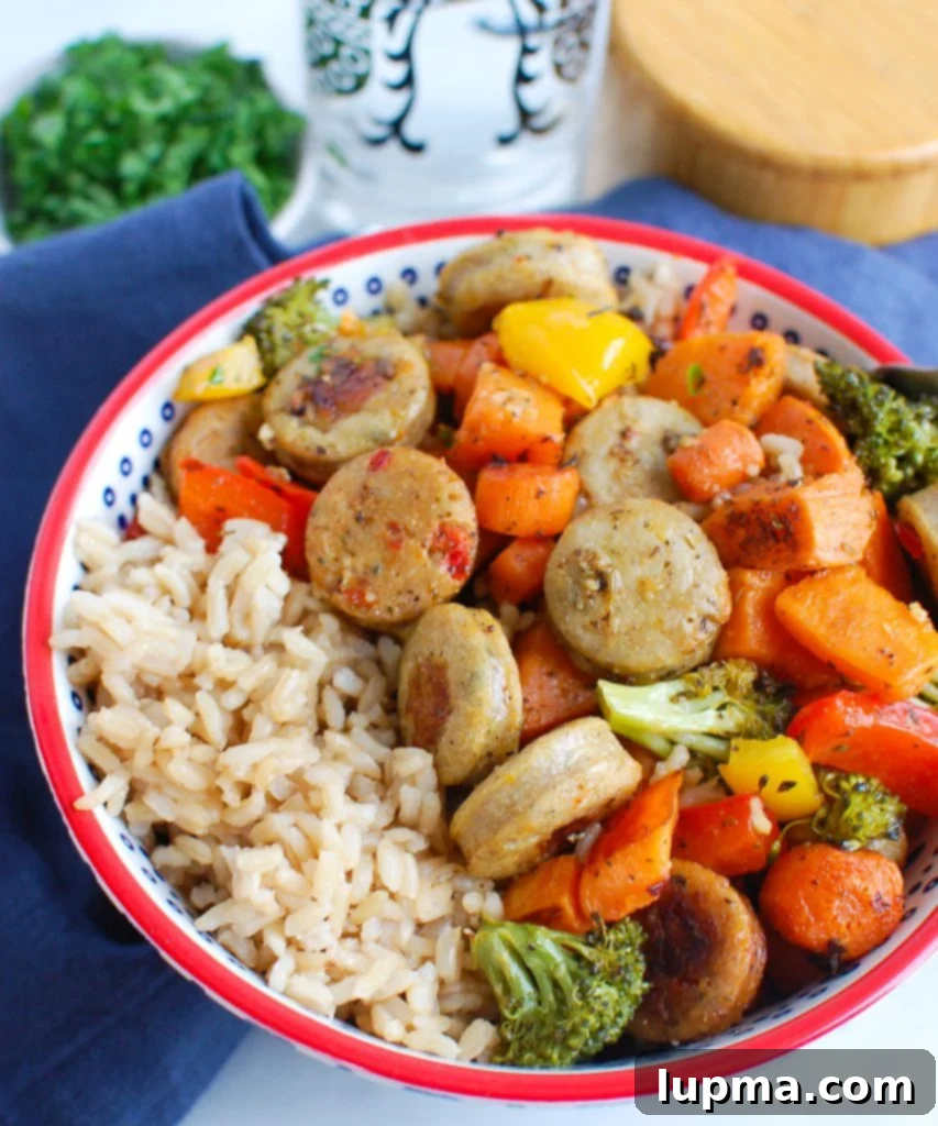 Golden Roasted Chicken Sausage and Garden Veggies 4 Close-up of a serving of Sheet Pan Chicken Sausage and Vegetables in a bowl, showing roasted sausage slices and colorful vegetables.