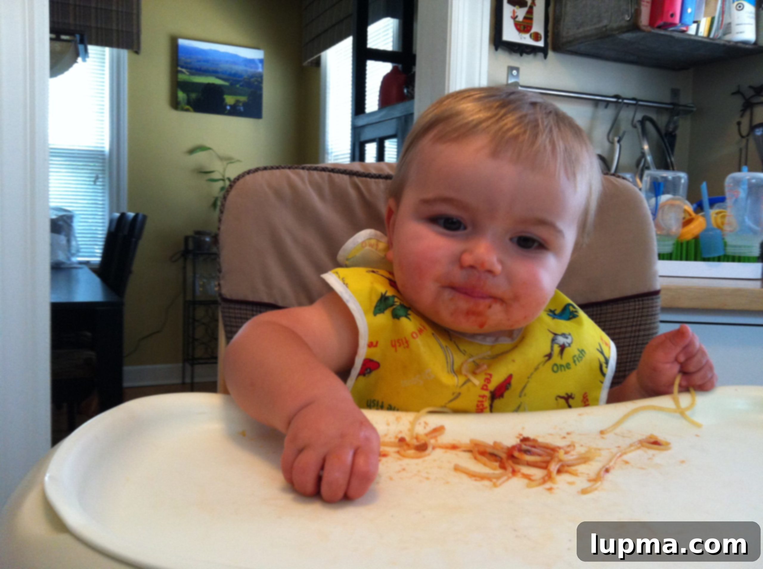 Toddler joyfully eating spaghetti for the first time, making a delightful mess