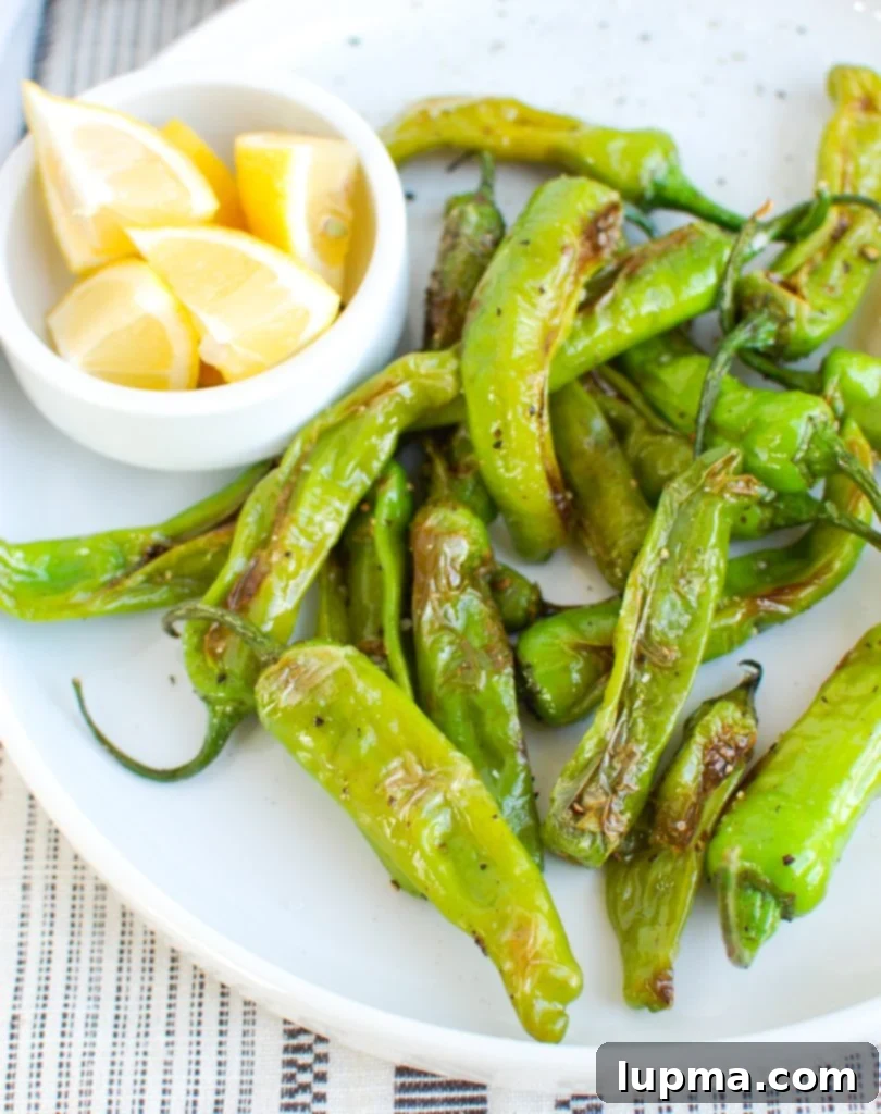 Mastering Shishito Peppers 5 A vibrant platter of perfectly cooked Shishito Peppers, generously garnished with multiple fresh lemon wedges, showcasing a healthy and quick appetizer or side dish.