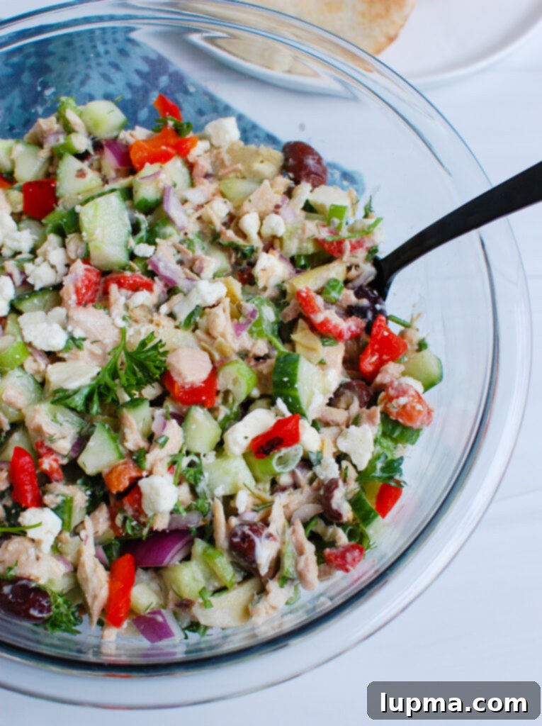 Sun-Kissed Mediterranean Tuna Medley 5 Mediterranean Tuna Salad in a bowl with a spoon, showing a close-up of the ingredients.