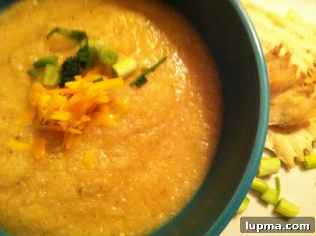 A steaming bowl of Skinny Baked Potato Soup, garnished with fresh chives and a dollop of sour cream, promising warmth and flavor.