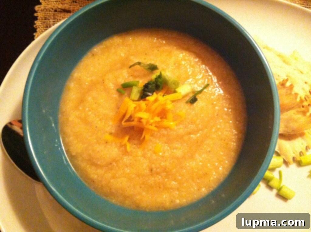 A close-up shot of a bowl of Skinny Baked Potato Soup, perfectly garnished and ready to be enjoyed, emphasizing its inviting texture and warmth.