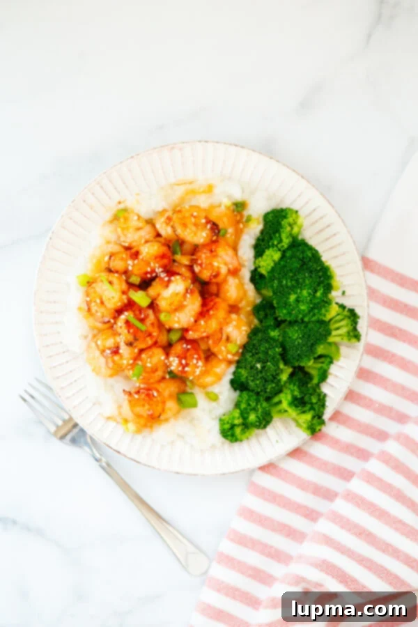 Sweet Heat Sriracha Shrimp 3 Close-up of Honey Garlic Sriracha Shrimp on a white plate, garnished with green onions and sesame seeds