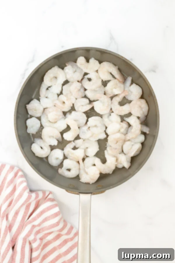 Sweet Heat Sriracha Shrimp 5 Honey Garlic Sriracha Shrimp cooking in a large skillet, coated in a glossy sauce