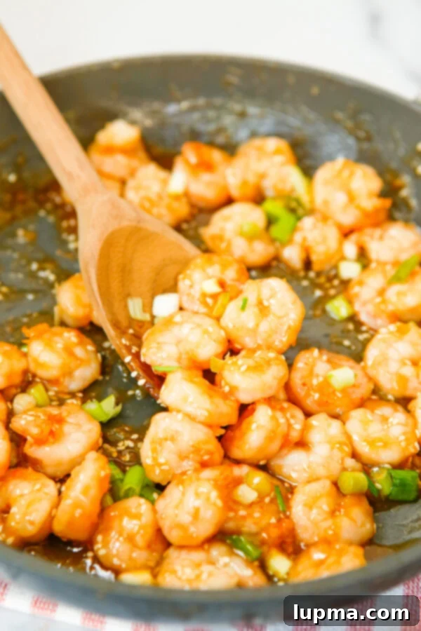 Sweet Heat Sriracha Shrimp 8 Close-up of Honey Garlic Sriracha Shrimp in a skillet with a serving spoon, garnished