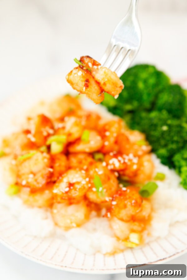 Sweet Heat Sriracha Shrimp 9 A forkful of Honey Garlic Sriracha Shrimp with green onions, showcasing the glazed texture