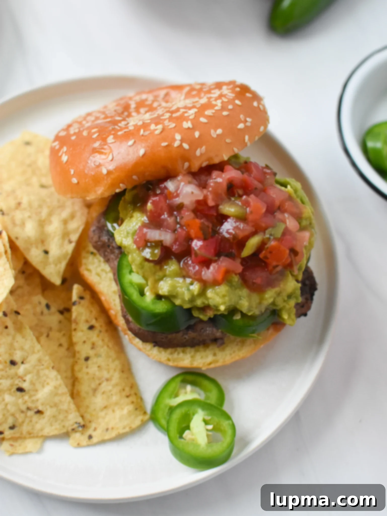 Southwest Sensation Burger 3 Tex Mex Burger with jalapeños on a wooden board.