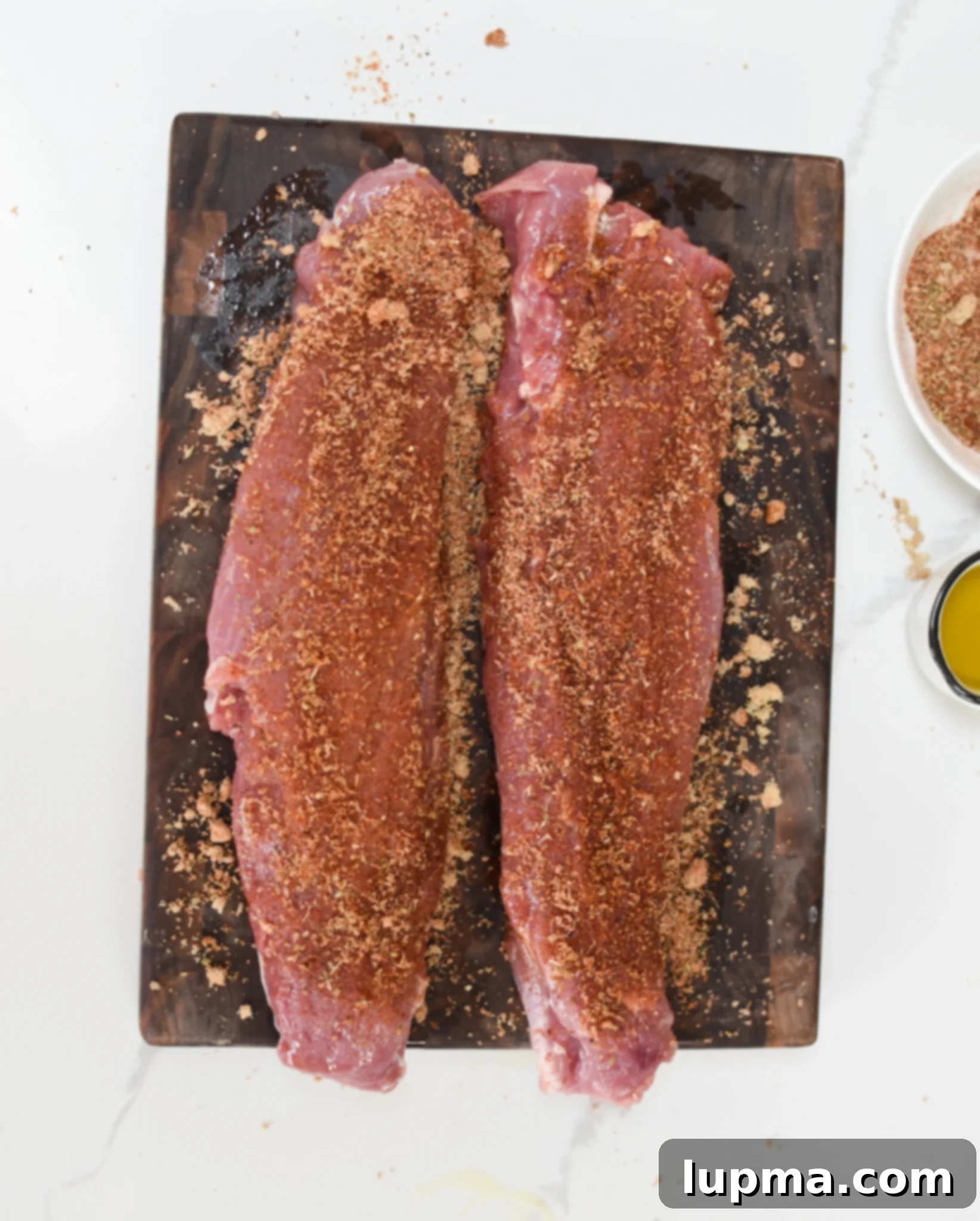 Juicy Air Fryer Pork Tenderloin 5 Air Fryer Pork Tenderloin with rub on a cutting board, ready for the air fryer.