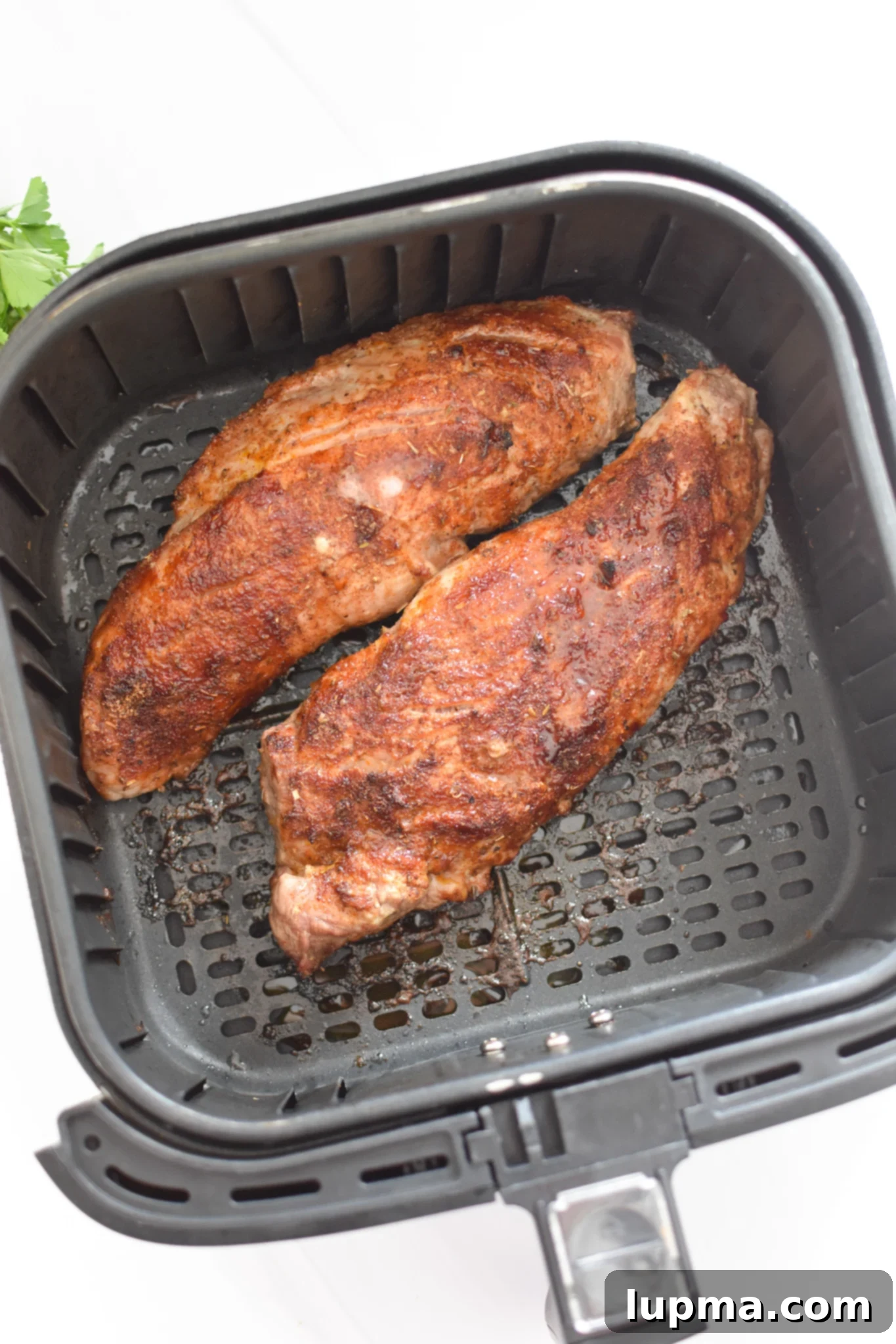Juicy Air Fryer Pork Tenderloin 6 Air Fryer Pork Tenderloin cooking in the air fryer basket.