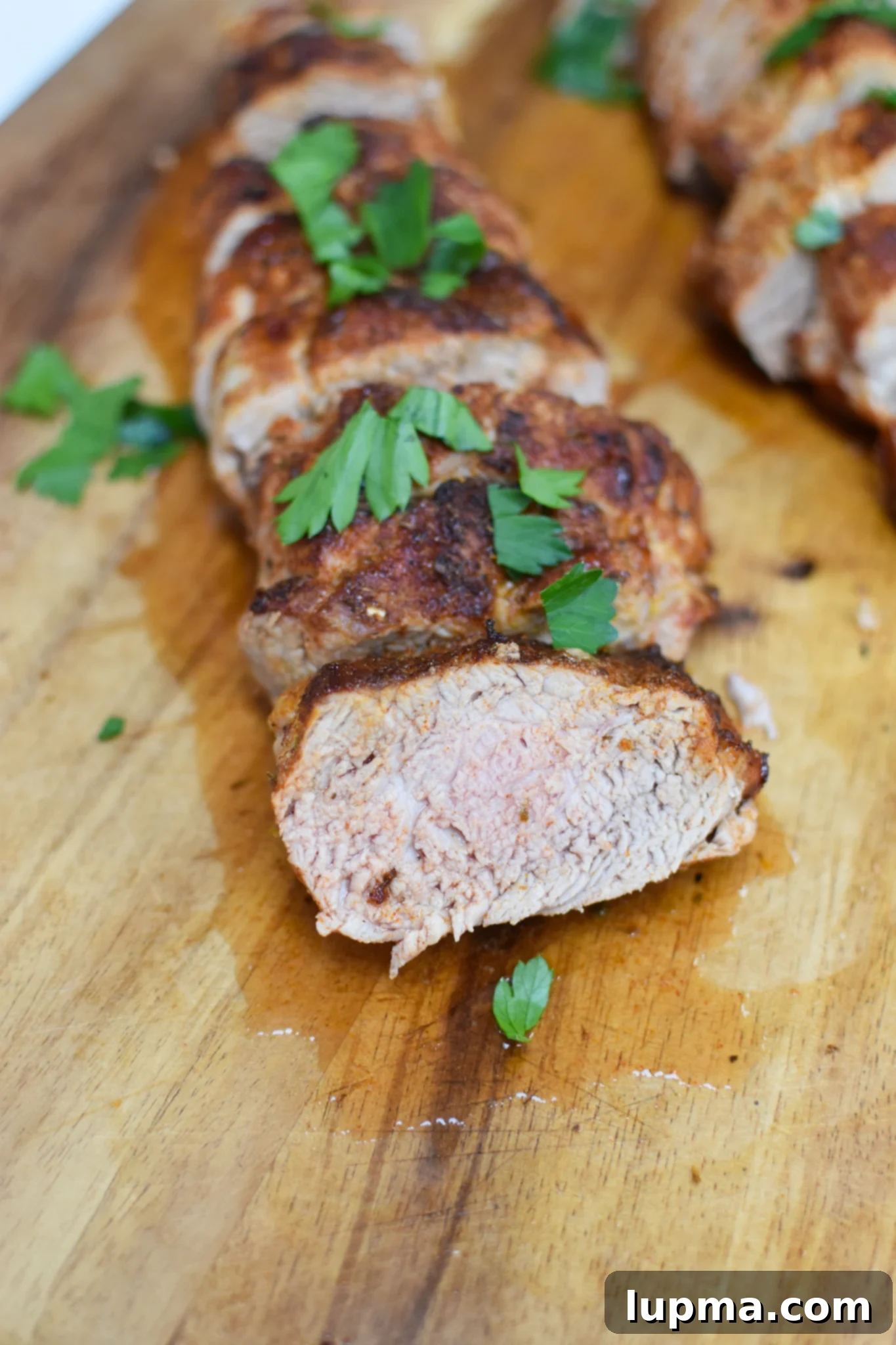 Juicy Air Fryer Pork Tenderloin 7 Air Fryer Pork Tenderloin on a cutting board, ready to be sliced.