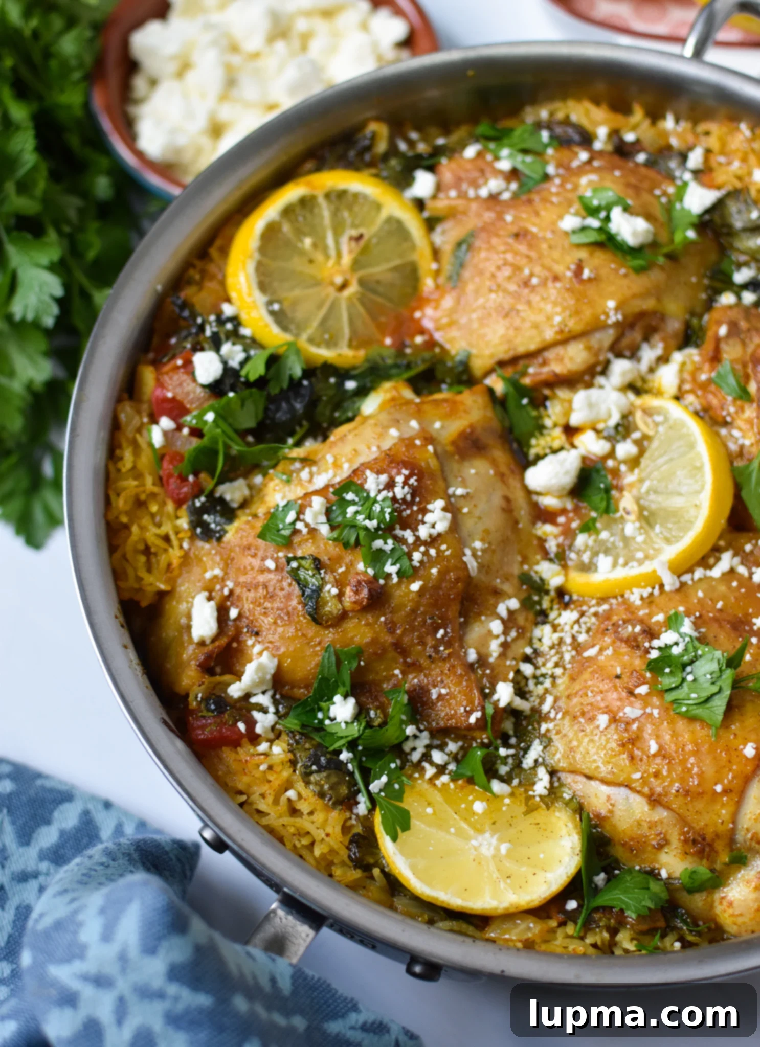 Sun-Kissed Mediterranean Chicken & Rice 2 A large pot filled with One Pot Mediterranean Chicken and Rice, garnished with fresh herbs and lemon slices.