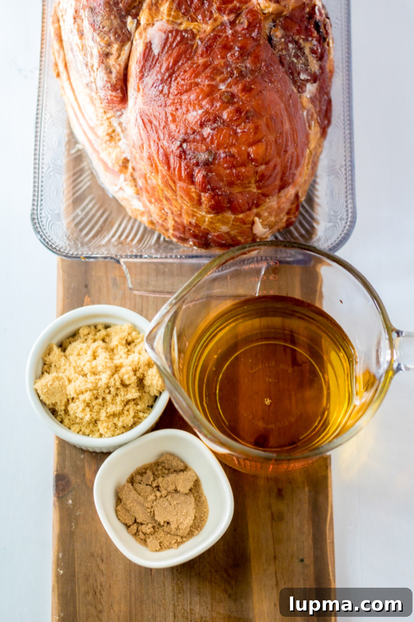 Sweet and Sticky Apple Cider Glazed Ham 3 Ingredients for Apple Cider Glazed Ham laid out on a cutting board.