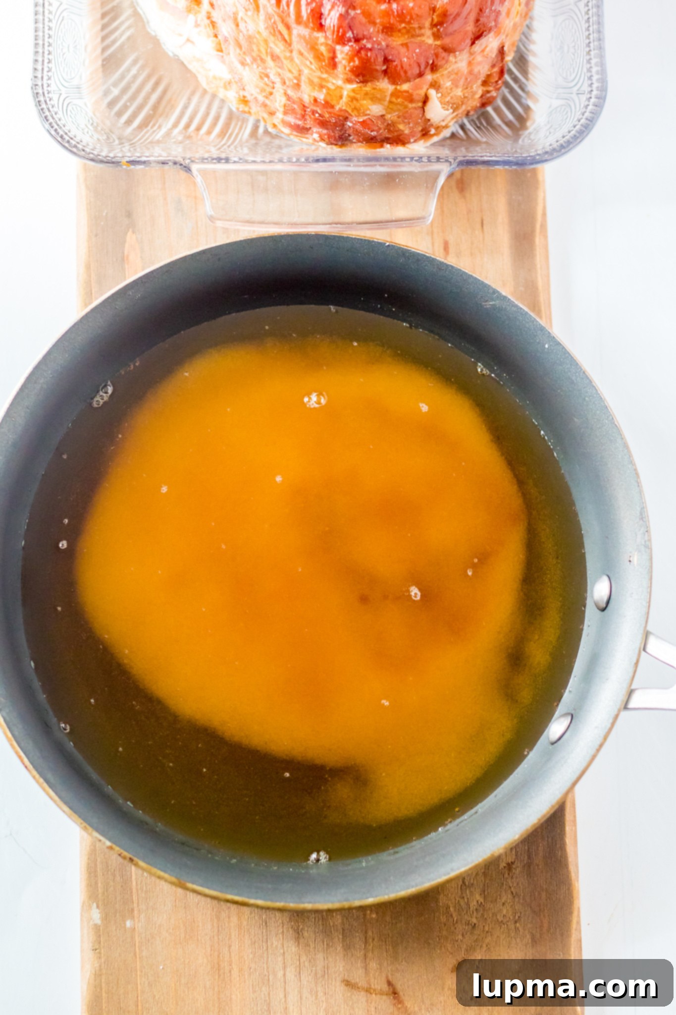 Sweet and Sticky Apple Cider Glazed Ham 5 Apple Cider Glaze simmering in a saucepan on the stovetop.