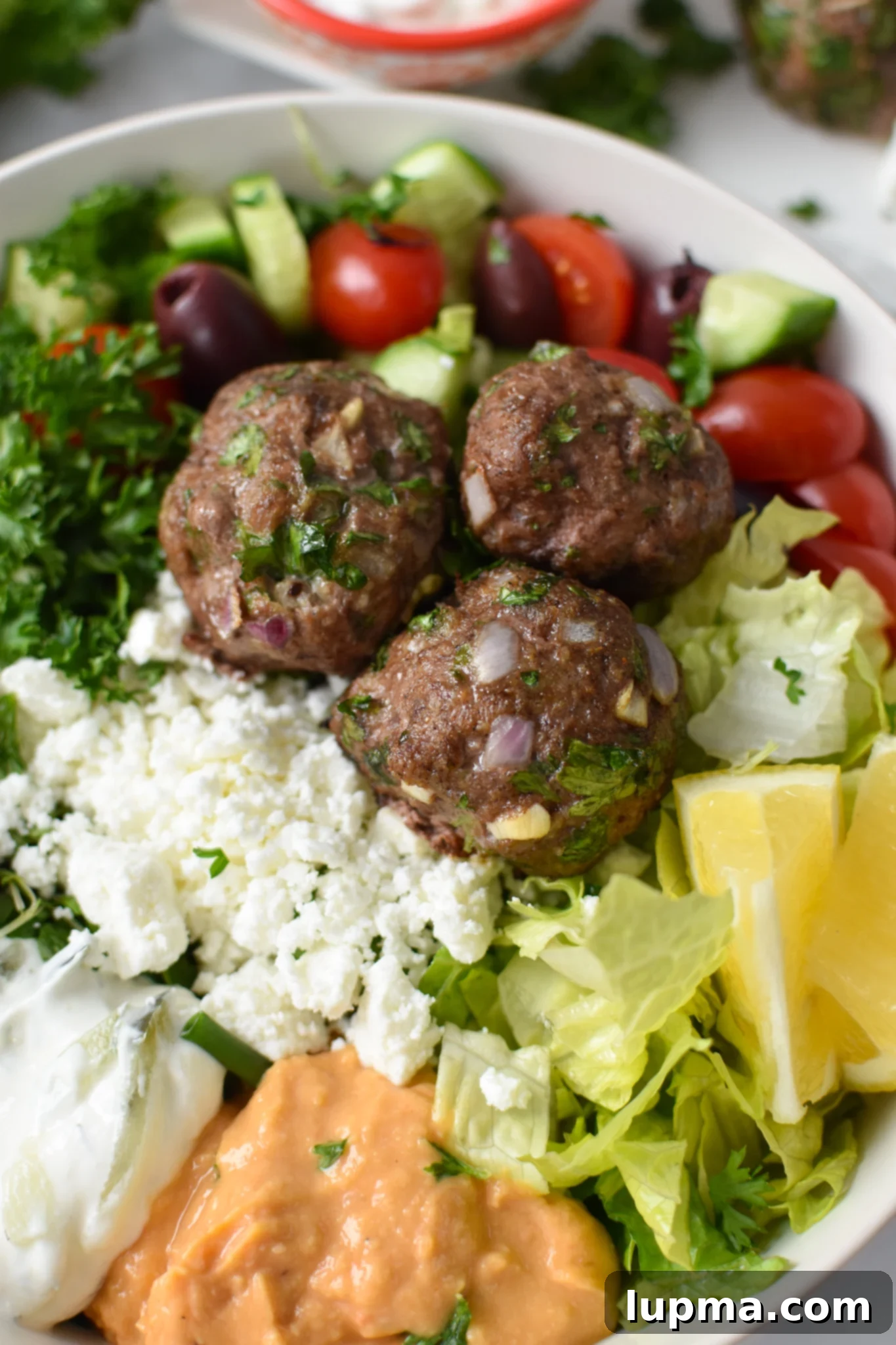 Mediterranean Golden Beef Meatballs 4 A close-up shot of Mediterranean Baked Beef Meatballs nestled in a hummus bowl, ready to be served.