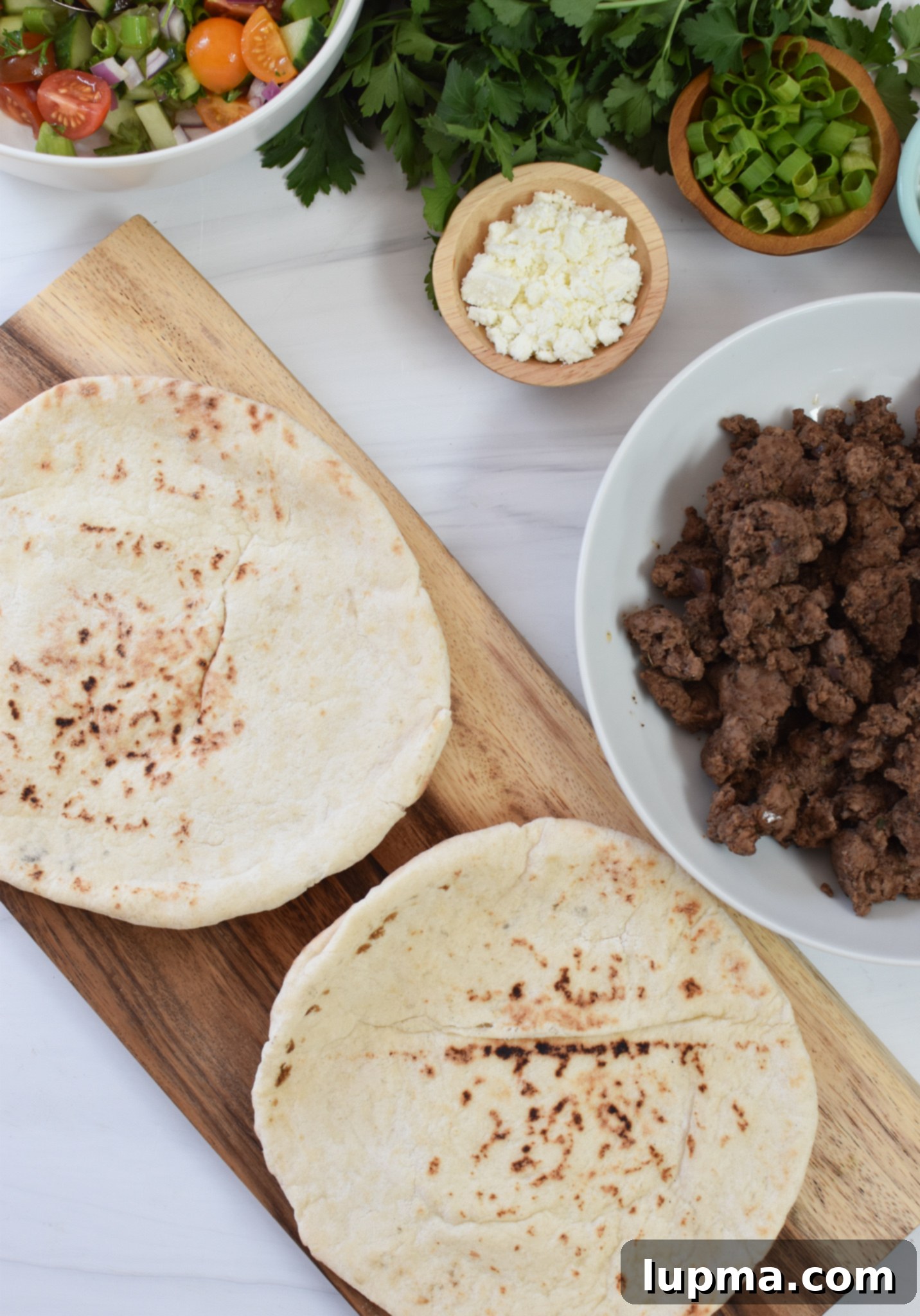 Spiced Lamb Pita Delight 5 Assembled spiced ground lamb pitas laid out on a cutting board, ready to be served.