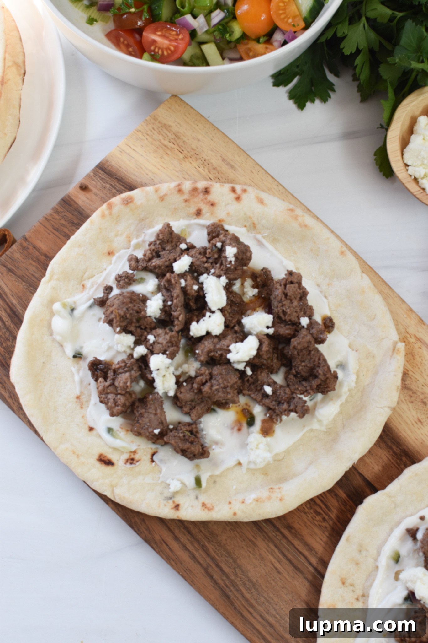 Spiced Lamb Pita Delight 6 Spiced Ground Lamb Pita, beautifully plated and garnished with fresh herbs and feta.