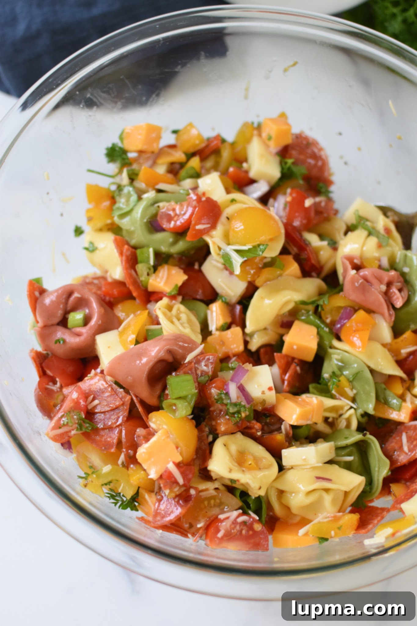 A large clear glass bowl showcasing the vibrant and colorful Easy Italian Tortellini Salad, ready for serving at a summer party.