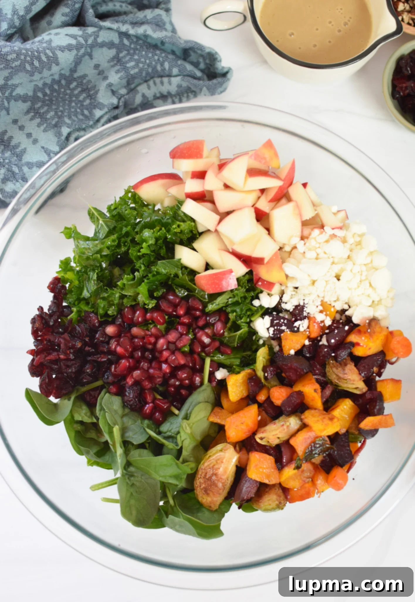 Autumn's Bounty Salad 8 A large salad bowl filled with kale, spinach, apples, pecans, cranberries, pomegranate, and goat cheese, ready for roasted vegetables.
