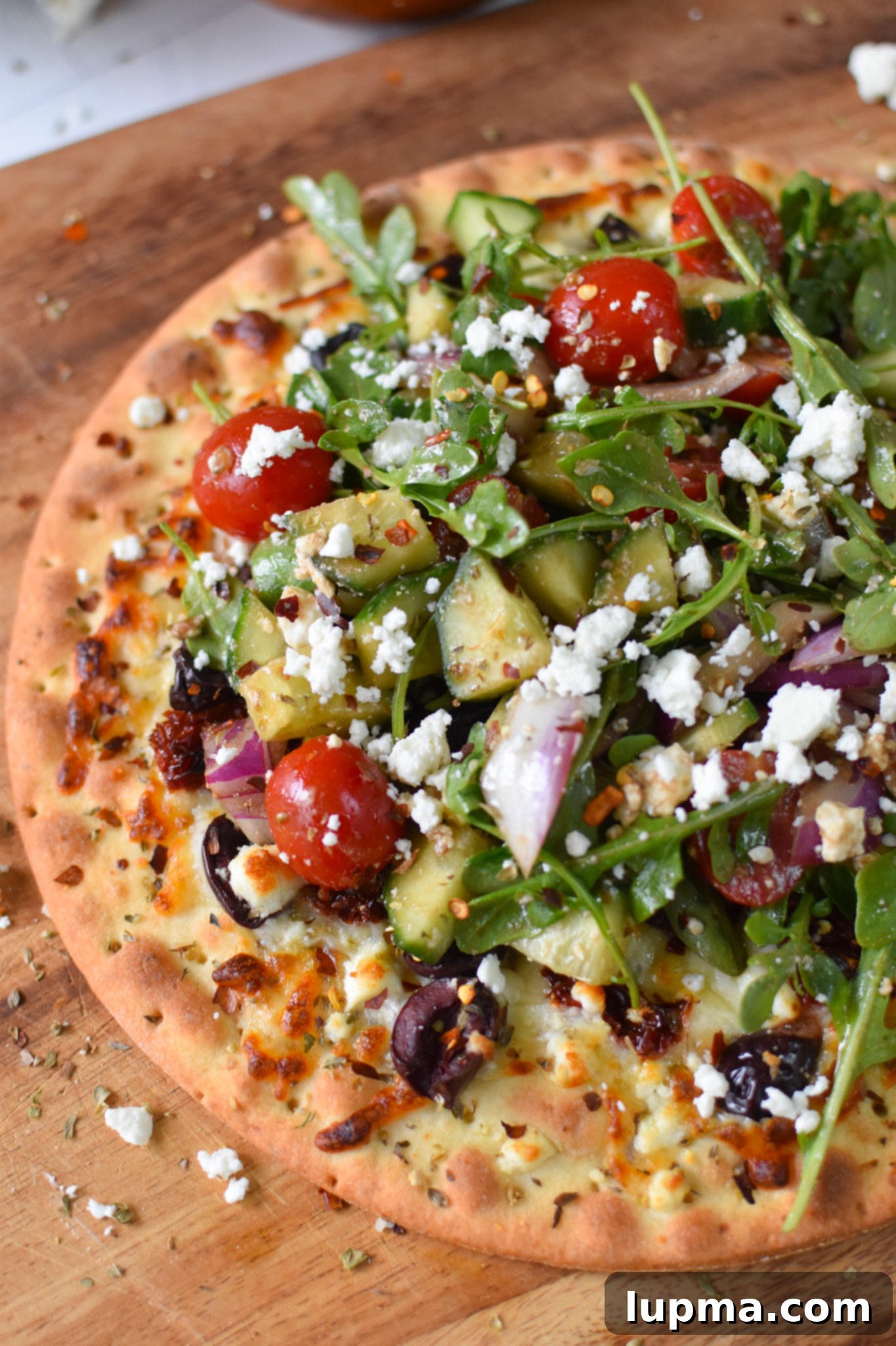 Hellenic Herb & Feta Pizza 7 Greek Pizza on a cutting board.