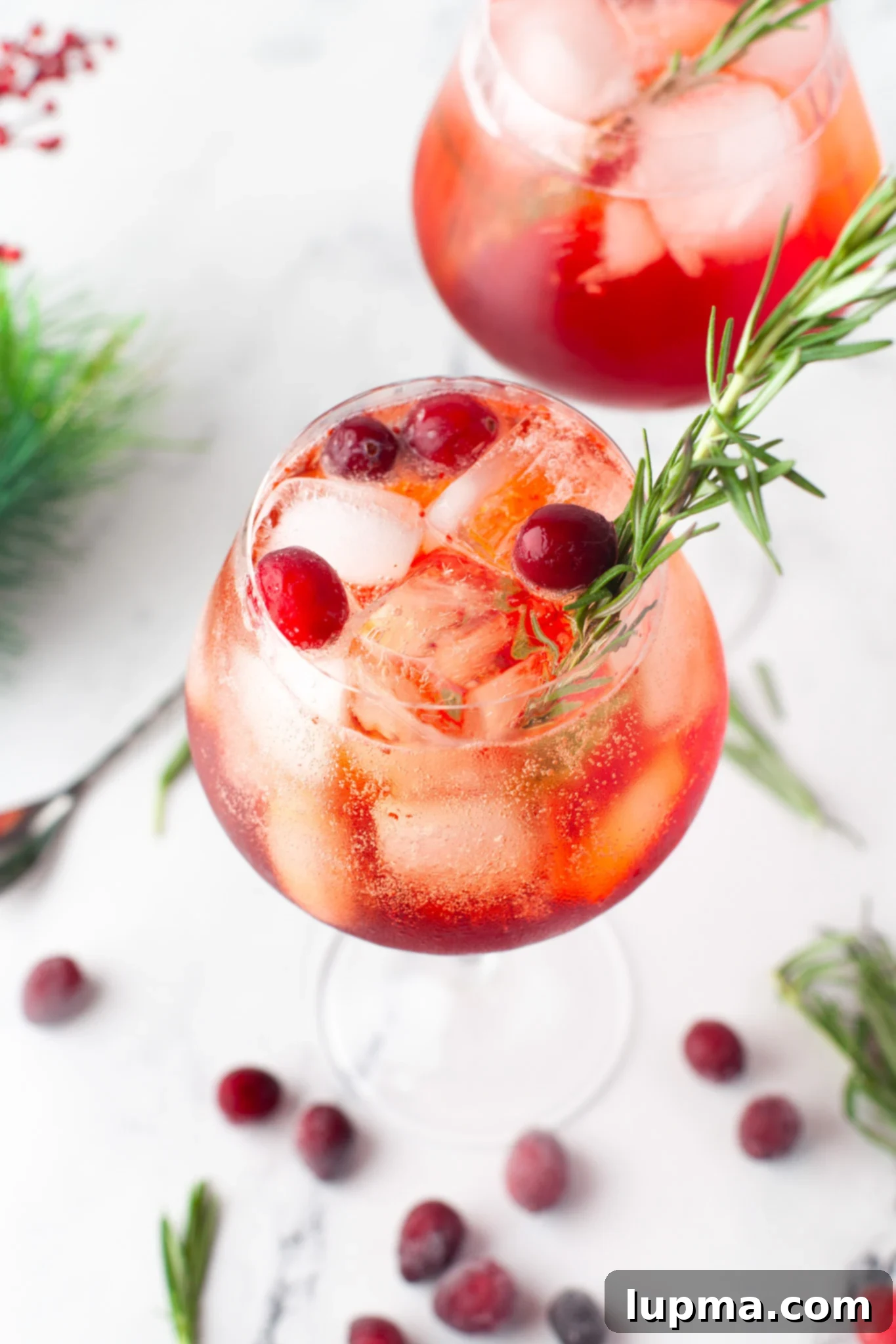 Vibrant Cranberry Aperol Spritz 2 Two glasses of Cranberry Aperol Spritz garnished with fresh cranberries and rosemary, perfect for holiday celebrations.