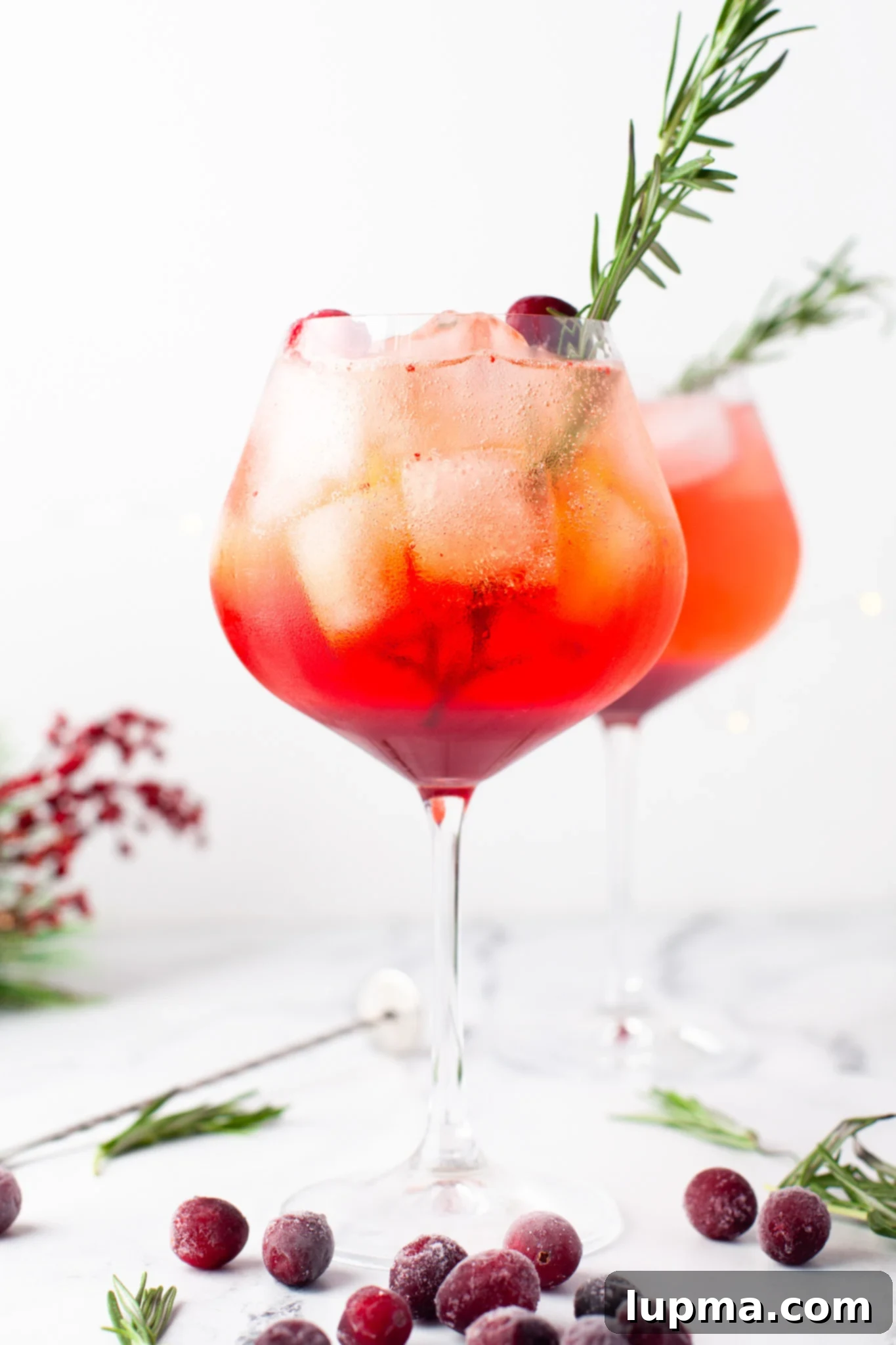 Vibrant Cranberry Aperol Spritz 8 A beautifully presented Cranberry Aperol Spritz, garnished with rosemary and cranberries, against a warm holiday backdrop.