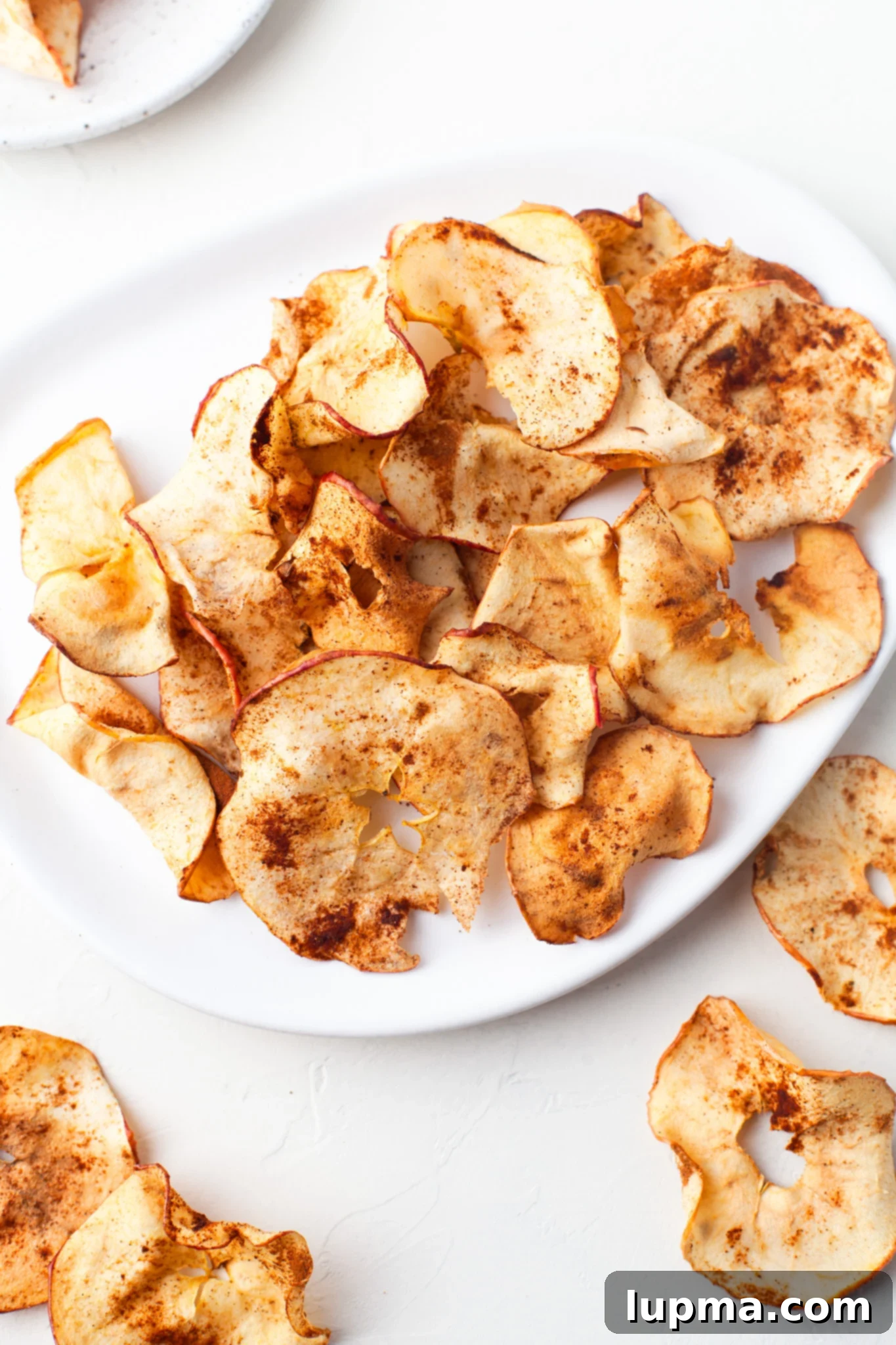 Quick & Crispy Air Fryer Apple Chips 4 Easy Air Fryer Apple Chips on a white plate, ready to be enjoyed.