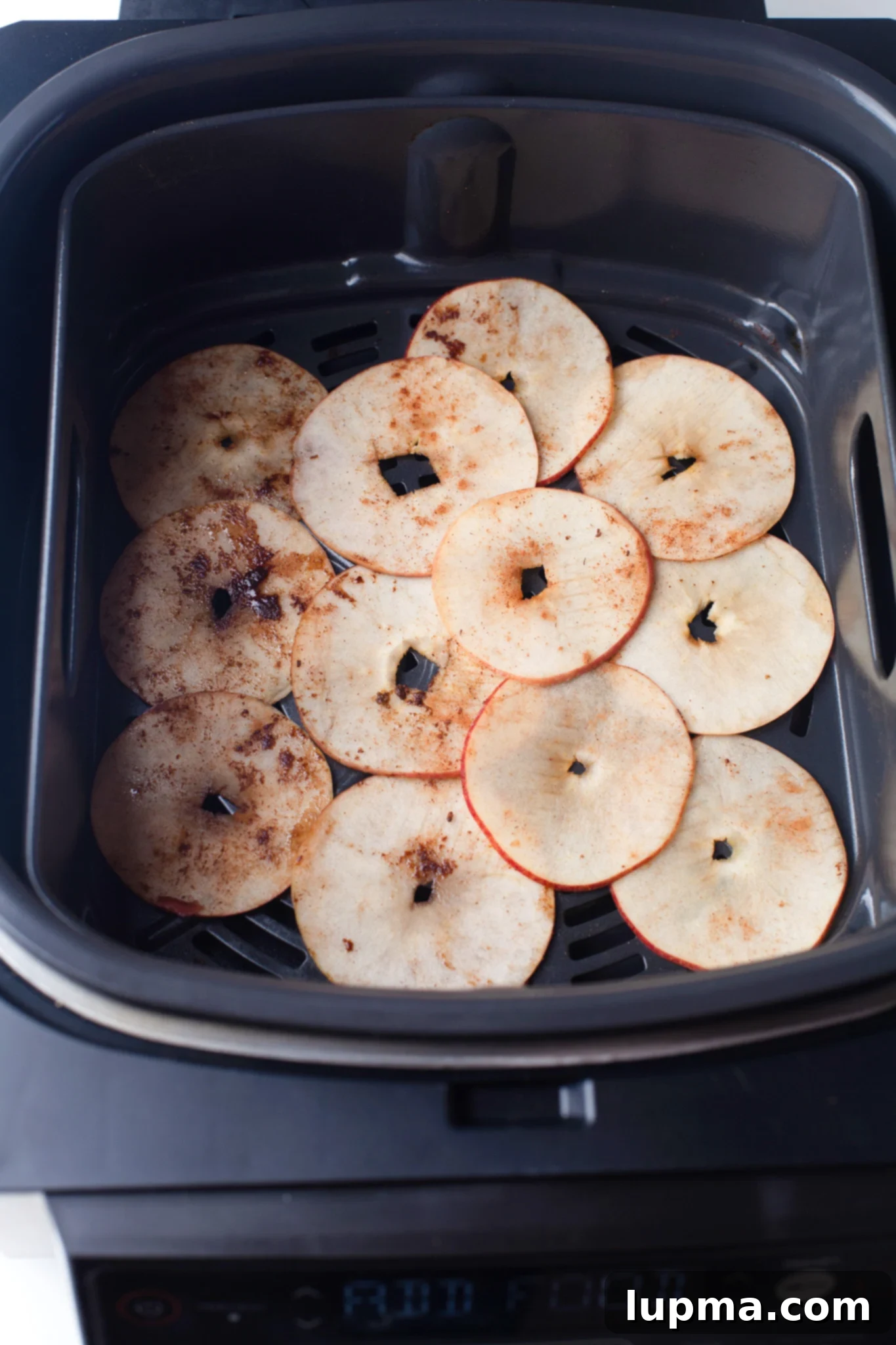 Quick & Crispy Air Fryer Apple Chips 8 Easy Air Fryer Apple Chips cooking in an air fryer basket.