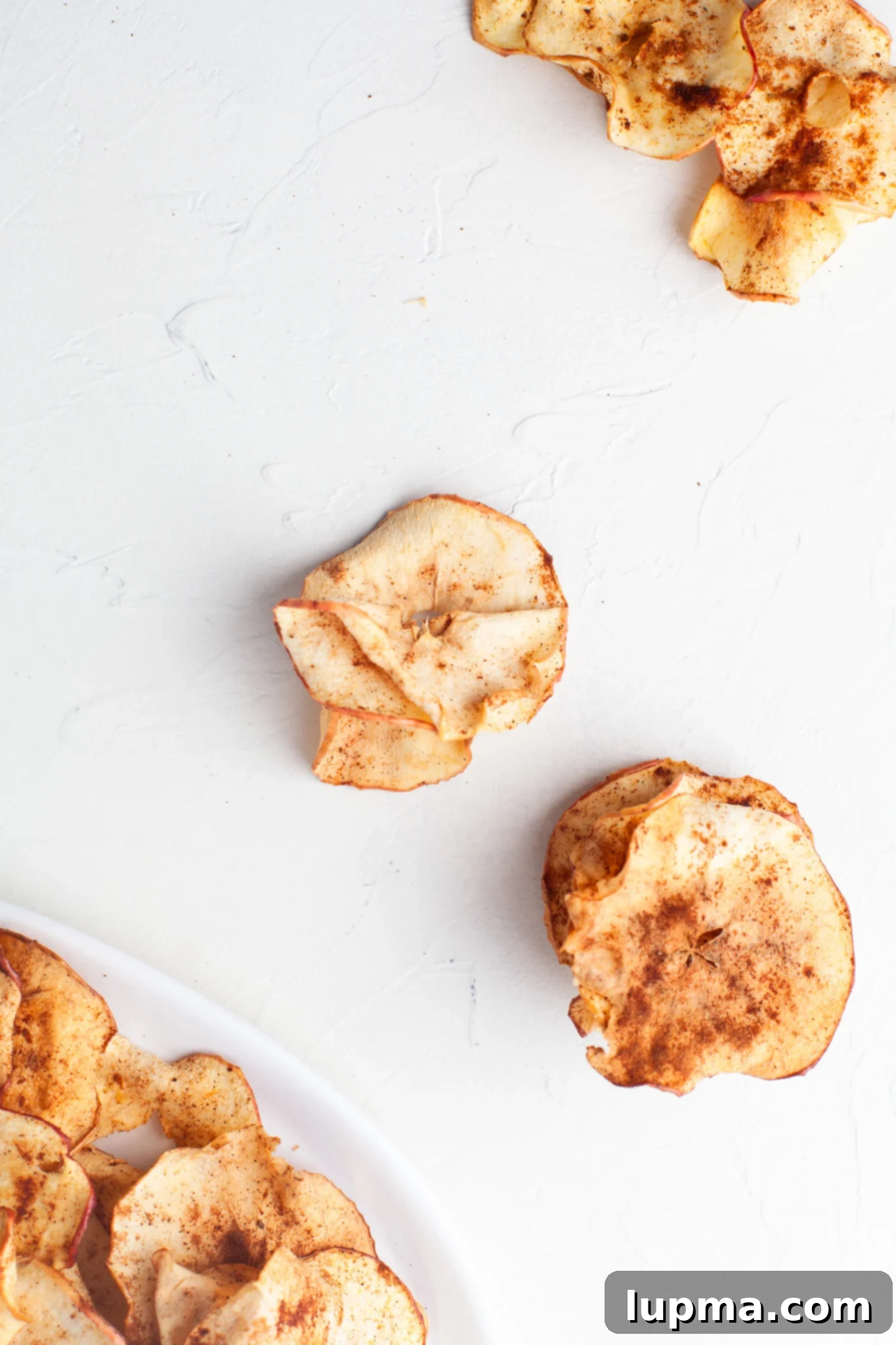 Quick & Crispy Air Fryer Apple Chips 10 Easy Air Fryer Apple Chips with a few apples scattered on a table.