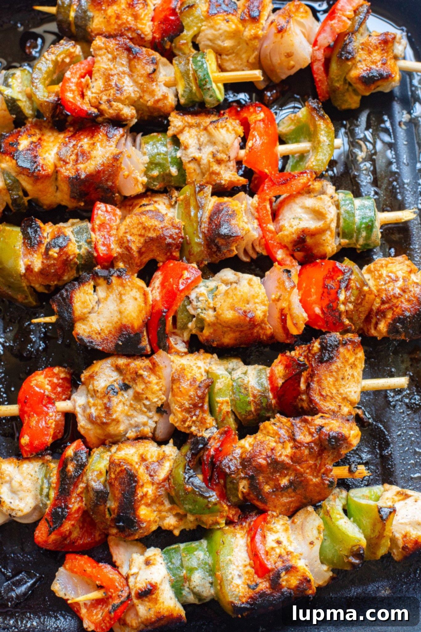 Zesty Greek Lemon Chicken Skewers 4 Greek Marinated Chicken Kabobs with Lemon cooking on an outdoor grill.