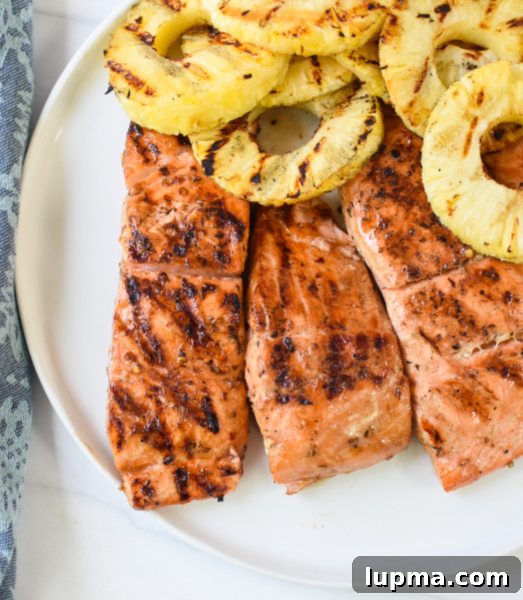 Aloha Grilled Salmon 9 Beautifully arranged Hawaiian Grilled Salmon fillets and grilled pineapple slices on a serving platter.
