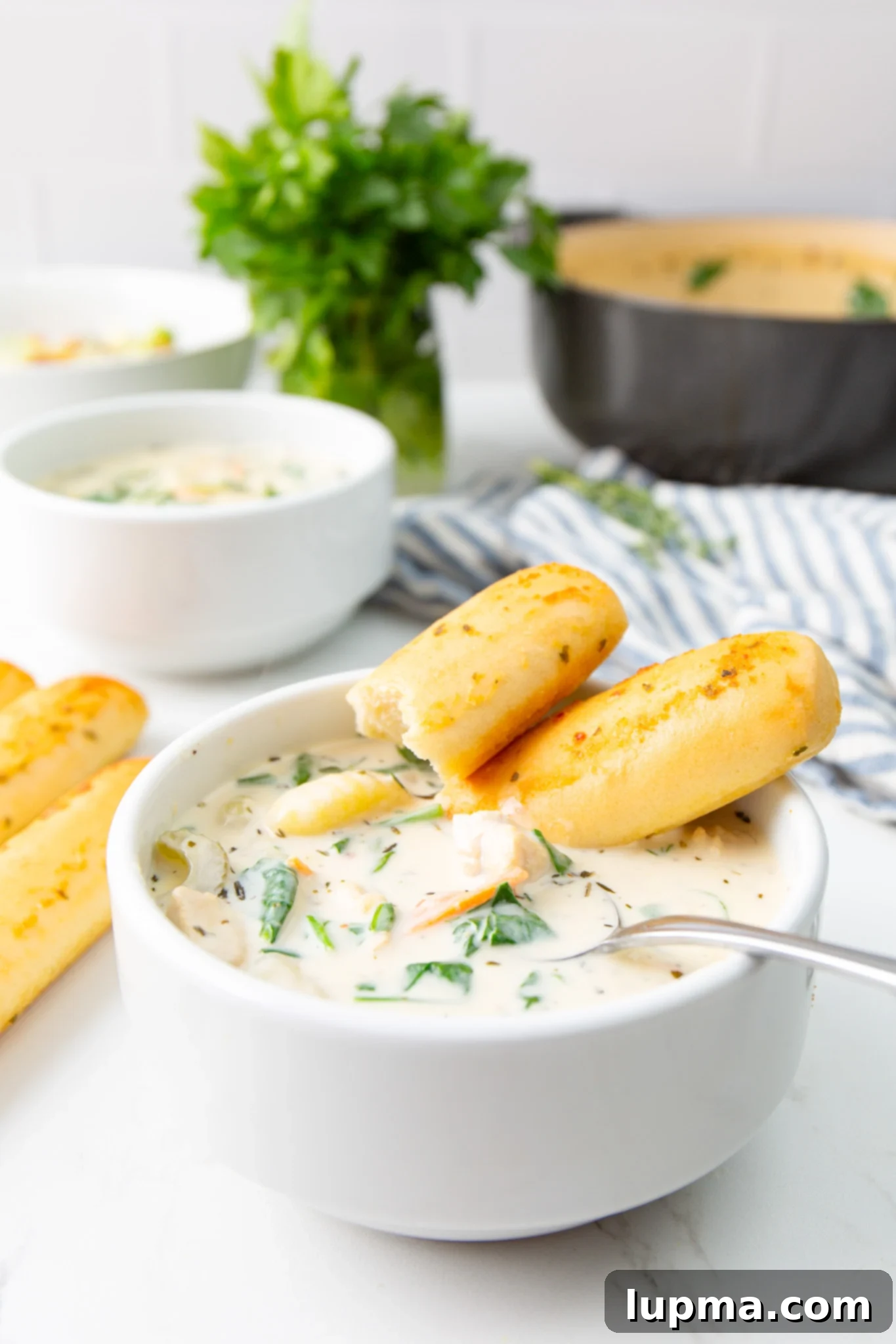 Homemade Olive Garden Style Chicken Gnocchi Soup 10 A bowl of creamy Copycat Olive Garden Chicken Gnocchi Soup served with breadsticks on the side, ready for a delicious meal.