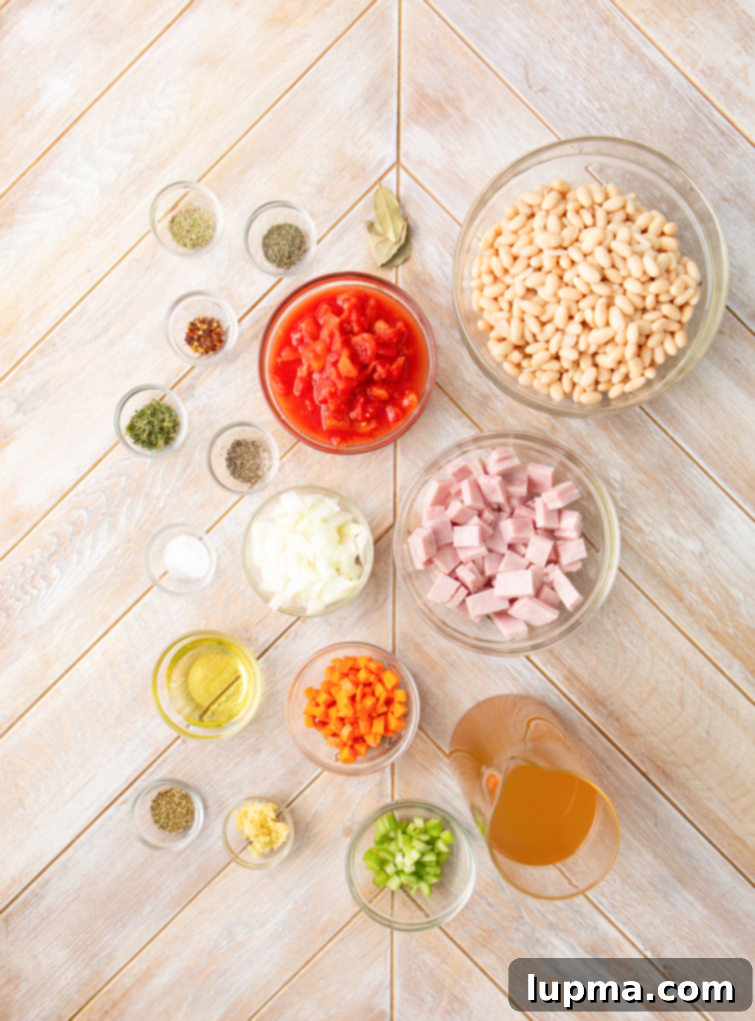Hearty Navy Bean Soup 4 Fresh ingredients laid out on a wooden board for Navy Bean Soup recipe preparation: beans, ham, carrots, celery, onion, and herbs.